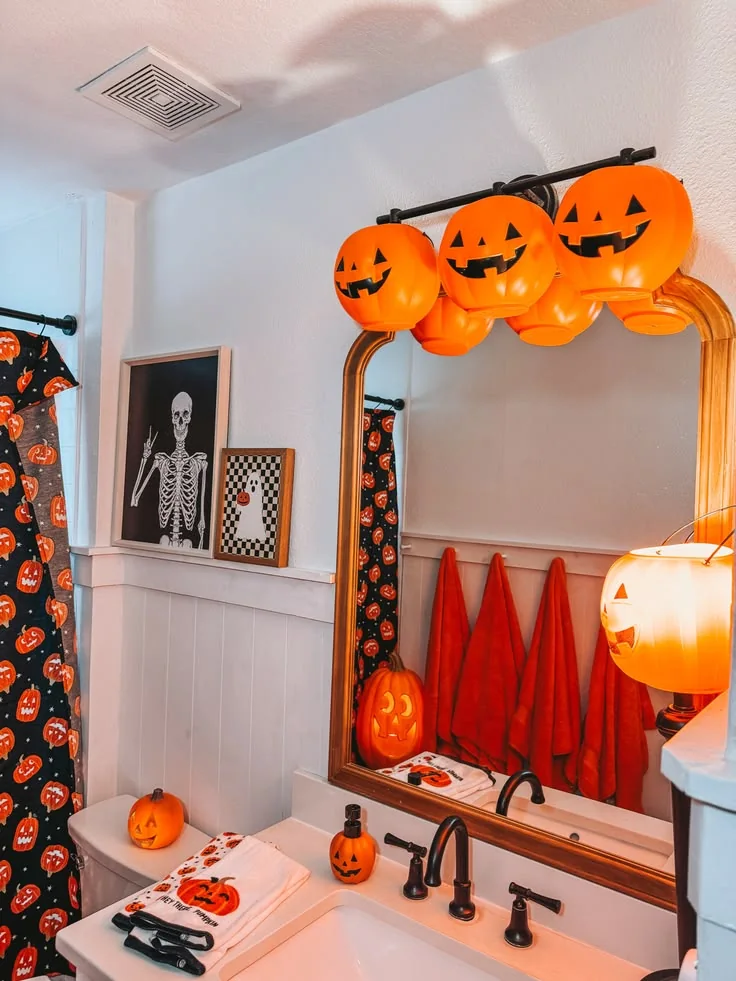 Halloween bathroom decorating idea 16: String Glowing Jack o Lantern Lights Over a Gold Mirror